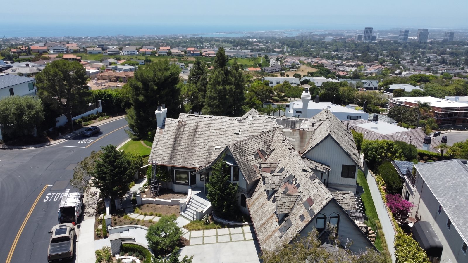 The same ocean-view home before the re-roof, with a tired, weathered roof