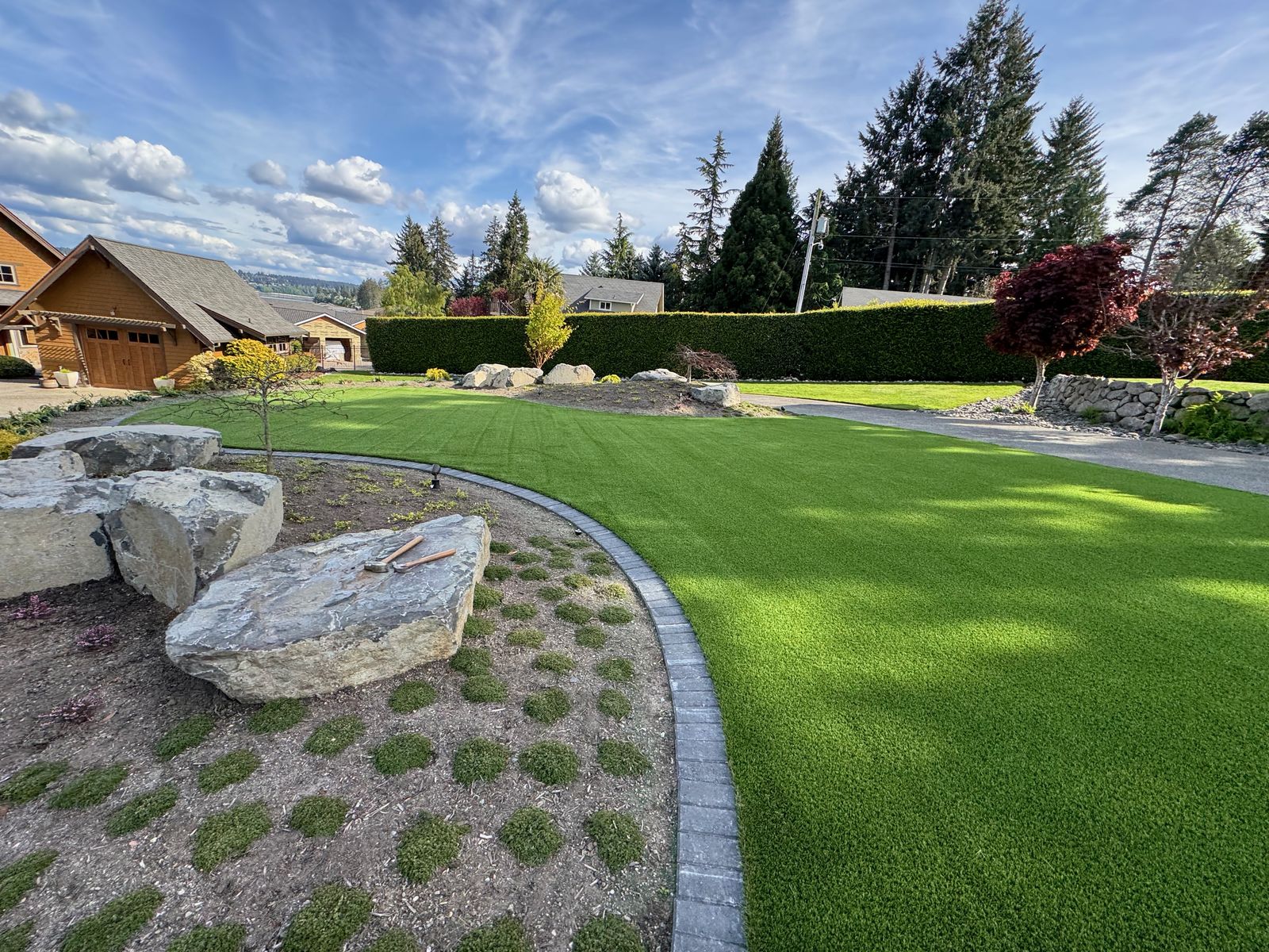 Lush artificial turf lawn with boulder landscape design